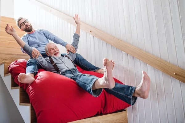 An adult hipster son and senior father indoors at home, having fun. — Stock Photo, Image