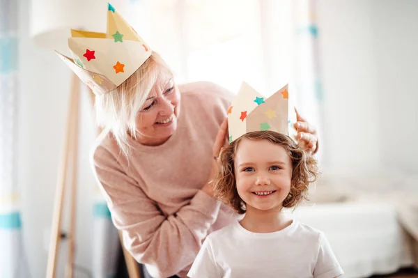 A portrait of small girl with grandmother at home, having fun. — Stock Photo, Image
