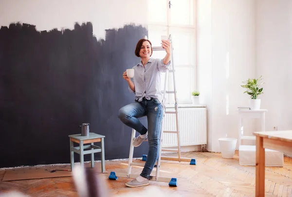 Porträt einer jungen Frau, die die Wand schwarz bemalt. Start-up für kleine Unternehmen. — Stockfoto