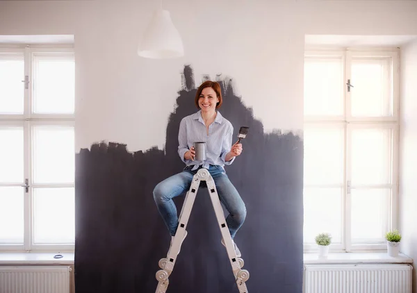 Um retrato de uma jovem mulher pintando parede preta. Uma startup de pequenas empresas . — Fotografia de Stock