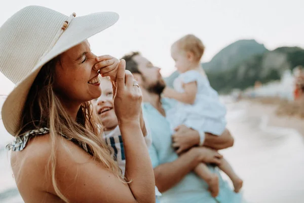 Una familia joven con dos niños pequeños divirtiéndose en la playa en las vacaciones de verano . — Foto de Stock