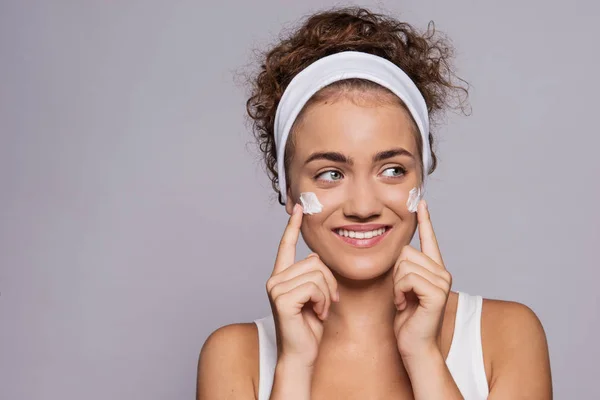 Retrato de una joven limpiando la cara en un estudio, belleza y cuidado de la piel . — Foto de Stock