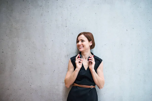 オフィスでコンクリートの壁に立っているヘッドフォンで若いビジネス女性. — ストック写真