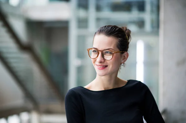 Porträt einer jungen Geschäftsfrau, die im Flur vor dem Büro steht. — Stockfoto