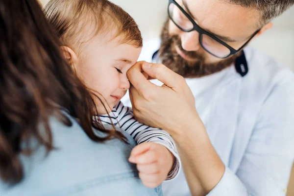 Una giovane famiglia con una bambina che piange in piedi in casa, sezione centrale . — Foto Stock