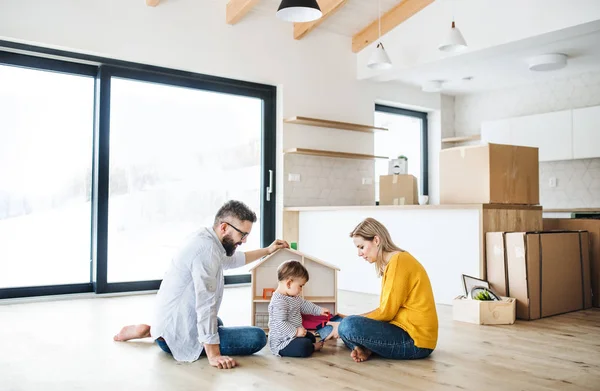 Yeni evinde hareketli bir yürümeye başlayan çocuk kızla genç aile portresi. — Stok fotoğraf