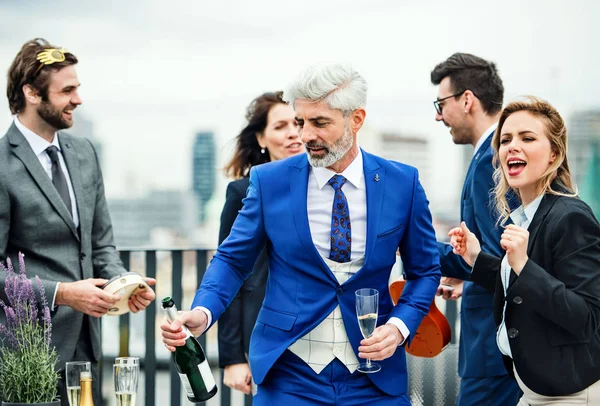 Een groep vrolijke zakenlui die een feestje hebben buiten op het dakterras in de stad. — Stockfoto