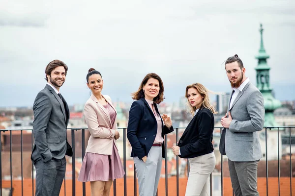 Un gruppo di uomini d'affari gioiosi in piedi all'aperto sulla terrazza sul tetto della città . — Foto Stock