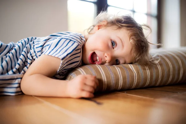 一个蹒跚学步的女孩躺在家里的地板上，玩. — 图库照片
