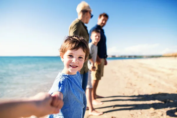 Familia joven con dos niños pequeños parados al aire libre en la playa . — Foto de Stock