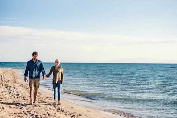 Ungt par som går utomhus på stranden, håller händerna. Kopiera utrymme. — Stockfoto