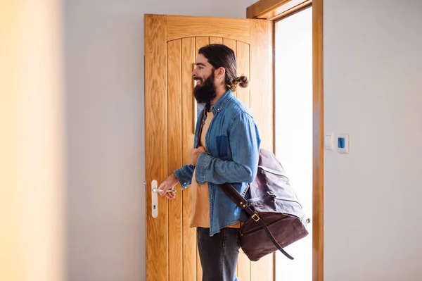 Homem jovem hipster com saco entrando porta da frente quando voltar para casa . — Fotografia de Stock