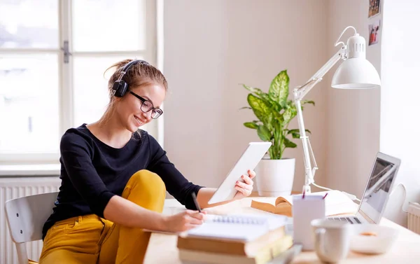 Una joven estudiante sentada en la mesa, usando tableta al estudiar. — Foto de Stock