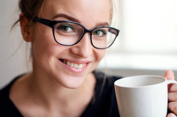 Un ritratto ravvicinato di una giovane studentessa, con in mano una tazza di caffè . — Foto Stock