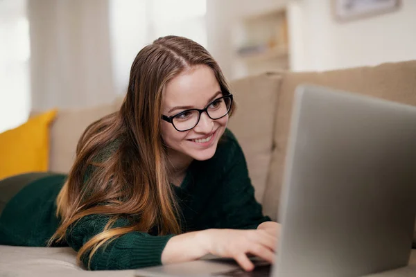 Egy fiatal női hallgató heverő, laptoppal, amikor tanul. — Stock Fotó
