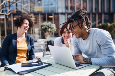 Avluda dizüstü bilgisayar kullanan bir grup genç işadamı, başlangıç konsepti.