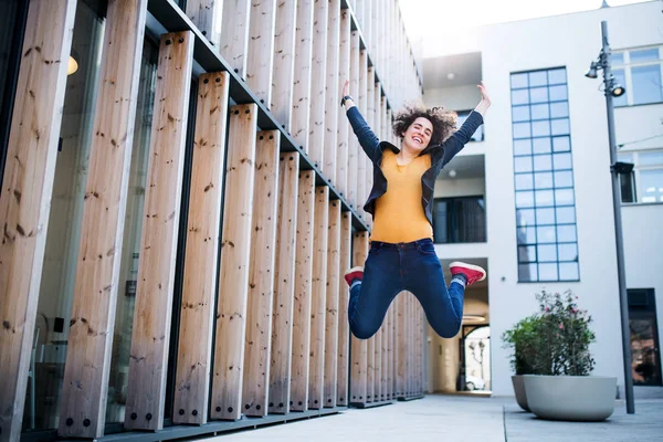 Una joven mujer de negocios saltando al aire libre, expresando emoción . — Foto de Stock