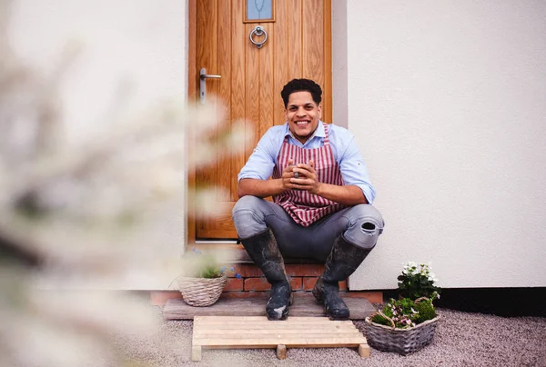 Un ritratto di un giovane giardiniere seduto davanti alla porta di casa . — Foto Stock