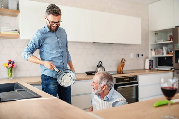 Vuxen hipster son och Senior far inomhus i köket hemma, Matlagning. — Stockfoto