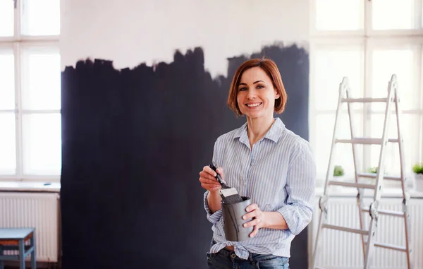 Een portret van de jonge vrouw schilderij muur zwart. Een opstarten van kleine ondernemingen. — Stockfoto