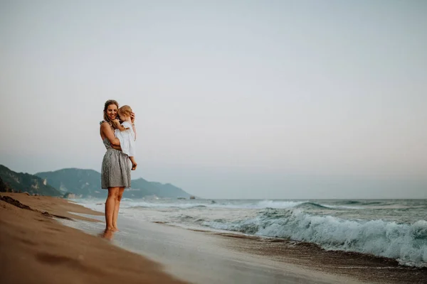 Madre joven con una niña en la playa en vacaciones de verano . —  Fotos de Stock