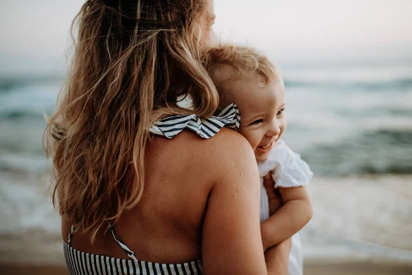 Primer plano de la madre joven con una niña en la playa en las vacaciones de verano . — Foto de Stock