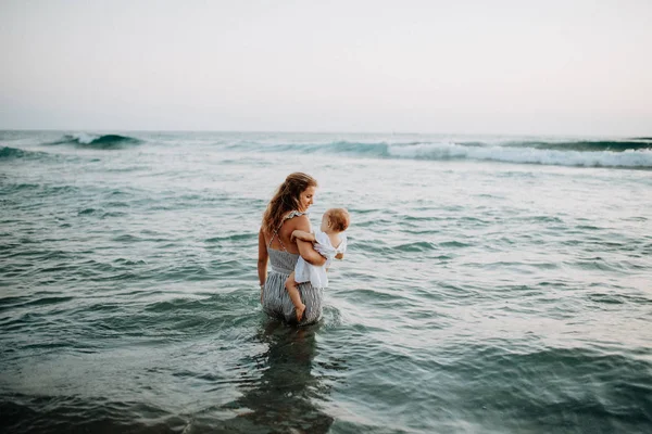 Vista posteriore di una giovane madre con una bambina che cammina in mare durante le vacanze estive . — Foto Stock