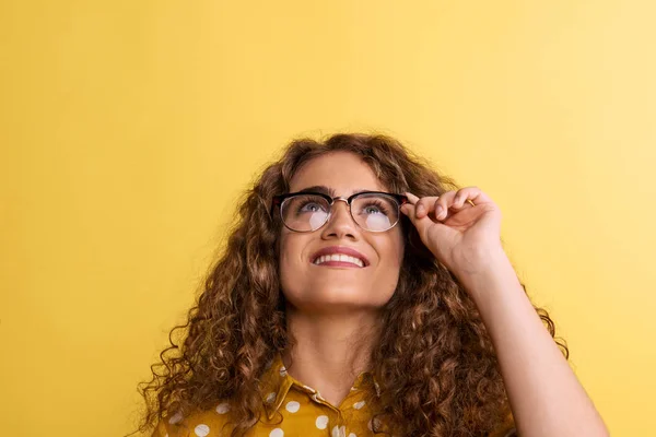 Porträt einer jungen Frau mit Brille in einem Atelier auf gelbem Hintergrund. — Stockfoto