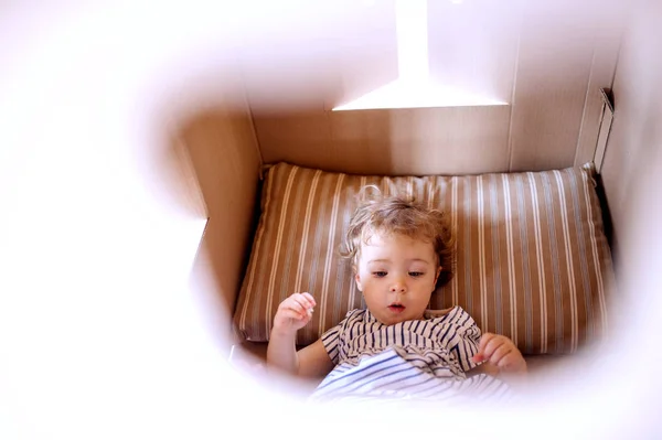 Una niña pequeña acostada en una casa de papel en casa, jugando . — Foto de Stock