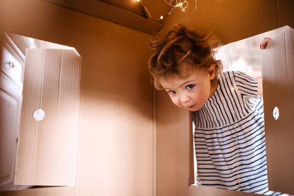 Een peuter meisje spelen met papier huis binnenshuis thuis. — Stockfoto