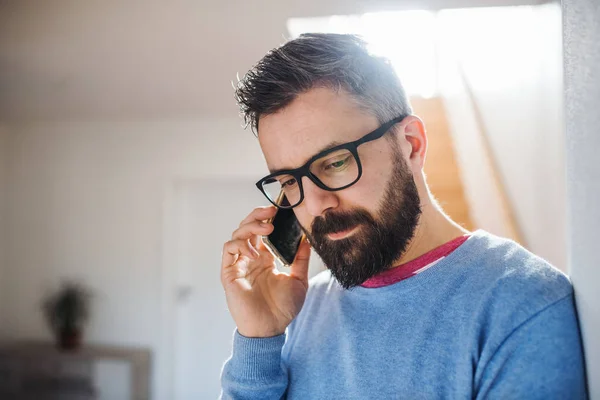 Ένας άνθρωπος με smartphone στέκεται μέσα στο σπίτι, κάνοντας ένα τηλεφώνημα. — Φωτογραφία Αρχείου