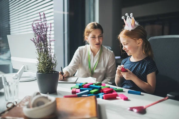 Kobieta interesu z małą córką siedzi w biurze, pracuje i gra. — Zdjęcie stockowe