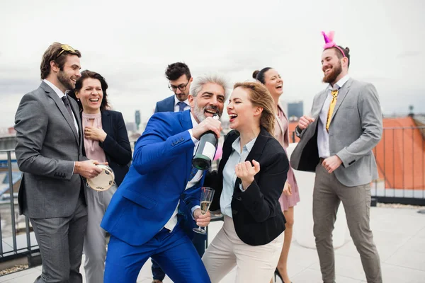 En grupp glada affärsmän som har en fest utomhus på takterrassen i staden. — Stockfoto