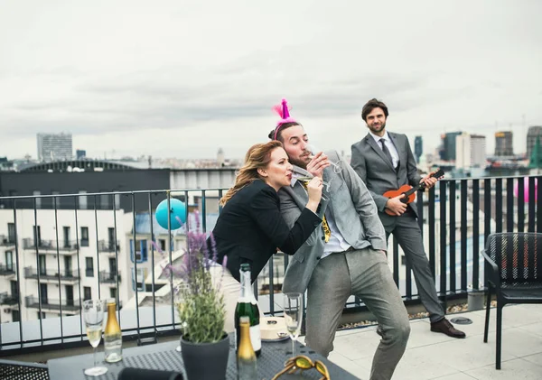Группа веселых бизнесменов, проводящих вечеринку на открытом воздухе на террасе на крыше в городе . — стоковое фото