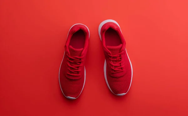 Uma foto de estúdio de um par de sapatos de corrida no fundo vermelho. Depósito plano . — Fotografia de Stock