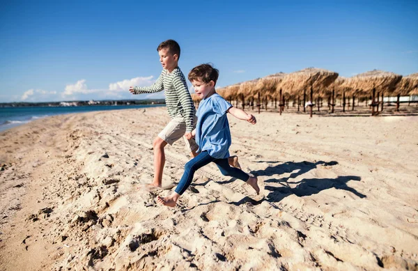 Dvě malé děti běžící venku na písečné pláži. — Stock fotografie