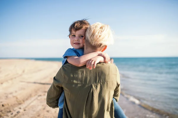 Achteraanzicht van jonge moeder met kleine dochter wandelen buitenshuis op het strand. — Stockfoto