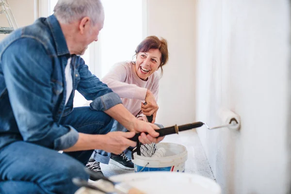 Senior coppia pittura pareti in nuova casa, concetto di trasferimento . — Foto Stock