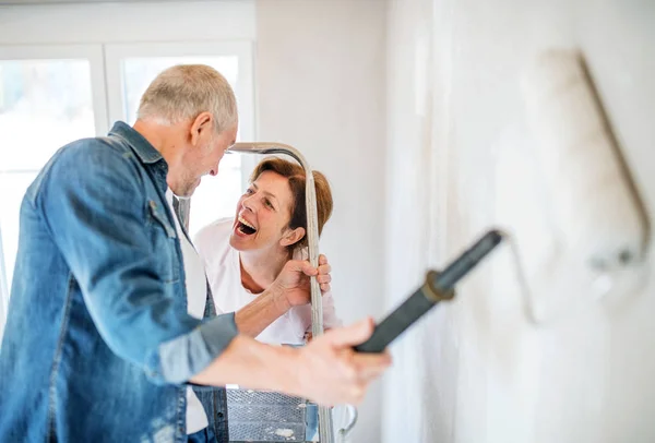 Senior coppia pittura pareti in nuova casa, concetto di trasferimento . — Foto Stock