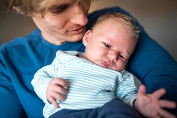 Evde yeni doğmuş bir bebek tutan genç baba bir ön görünüm. — Stok fotoğraf