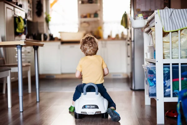 Una vista trasera de un niño pequeño con coche de juguete jugando en casa . — Foto de Stock