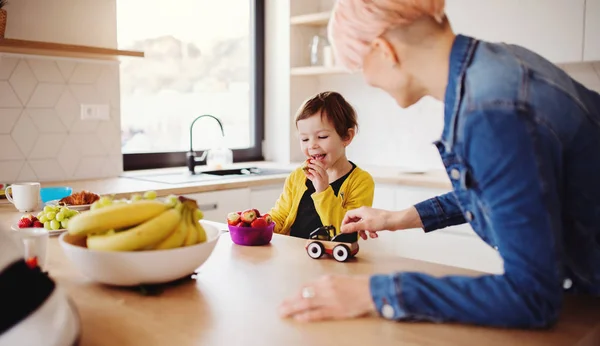 A young woman with a small daughter spending time together in a kitchen. — Stock Photo, Image