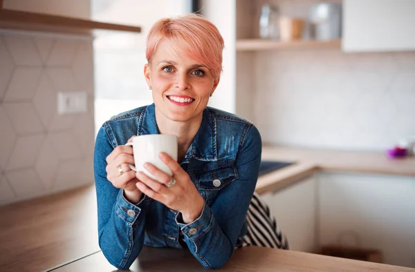 Eine junge attraktive Frau, die sich zu Hause in einer Küche auf eine Theke stützt. — Stockfoto