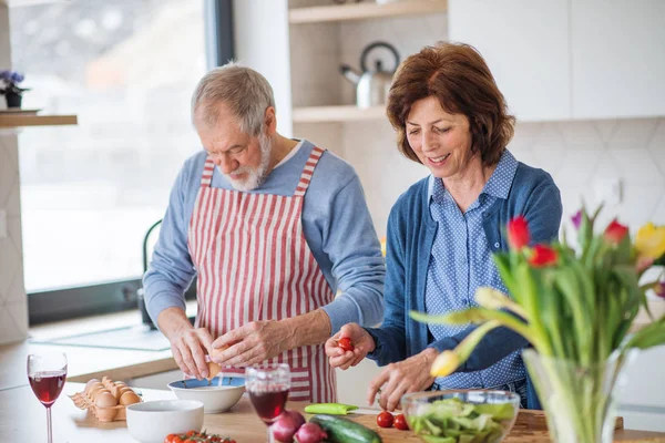 Um retrato de casal sênior apaixonado dentro de casa, cozinhar . — Fotografia de Stock