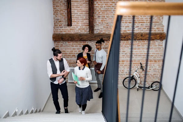 Group of young businesspeople walking up the stairs in indoors, talking. — Stock Photo, Image