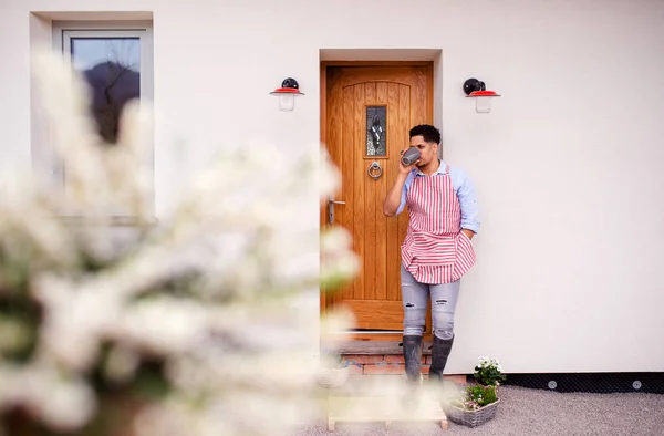 Um retrato do jovem jardineiro em pé na frente da porta em casa . — Fotografia de Stock