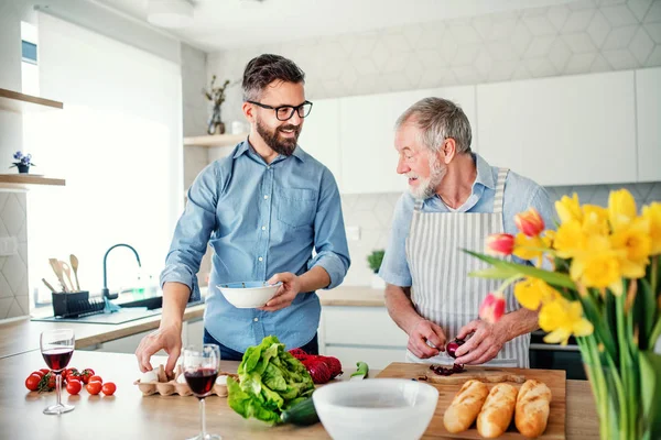 Un figlio hipster adulto e padre anziano in casa, che cucina . — Foto Stock