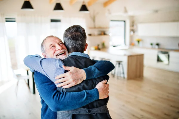 Un figlio hipster adulto e padre anziano in casa, che abbraccia . — Foto Stock