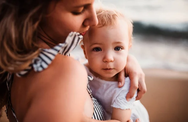 Close-up van jonge moeder met een peuter meisje op strand op zomervakantie. — Stockfoto