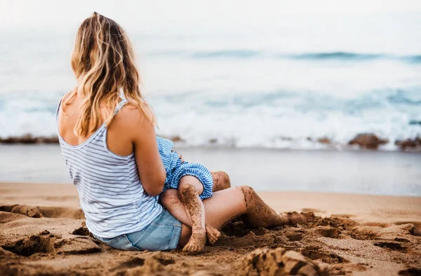 Ibu muda menyusui putri balita di pantai pada hari libur musim panas . — Stok Foto